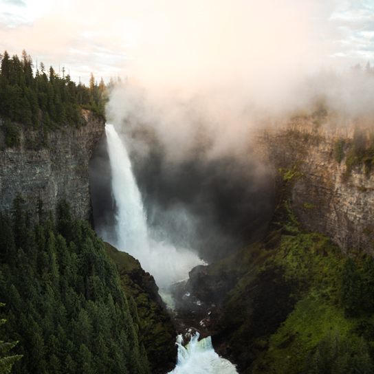 CleanBC-Square Image of a waterfall surrounded by pine trees and mountains.